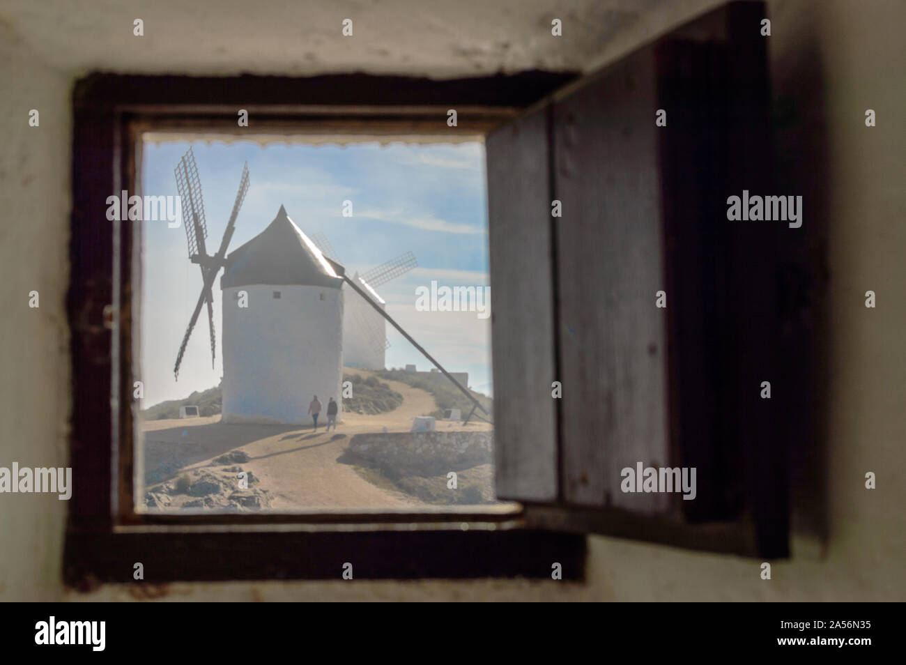 Windmühle gesehen, durch ein offenes Fenster einer anderen Mühle mit Nebel in Consuegra. 26. Dezember 2018. Consuegra Toledo Kastilien La Mancha Spanien Europa. Reisen Stockfoto