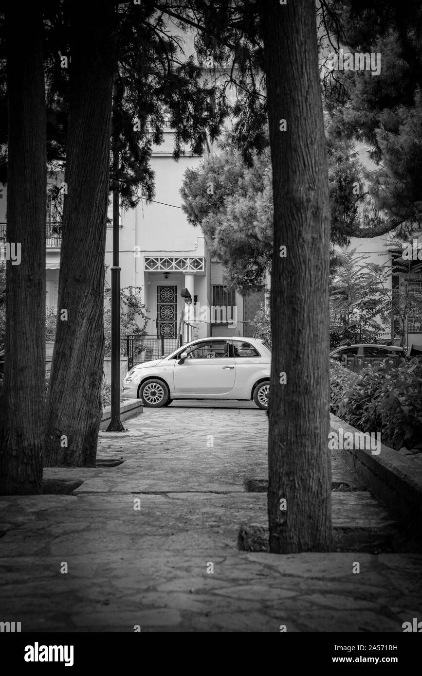 Weißes kompaktes Auto am Ende der Reihen von Zypressen Futter auf beiden Seiten der Stadt Athen Pflaster. Stockfoto