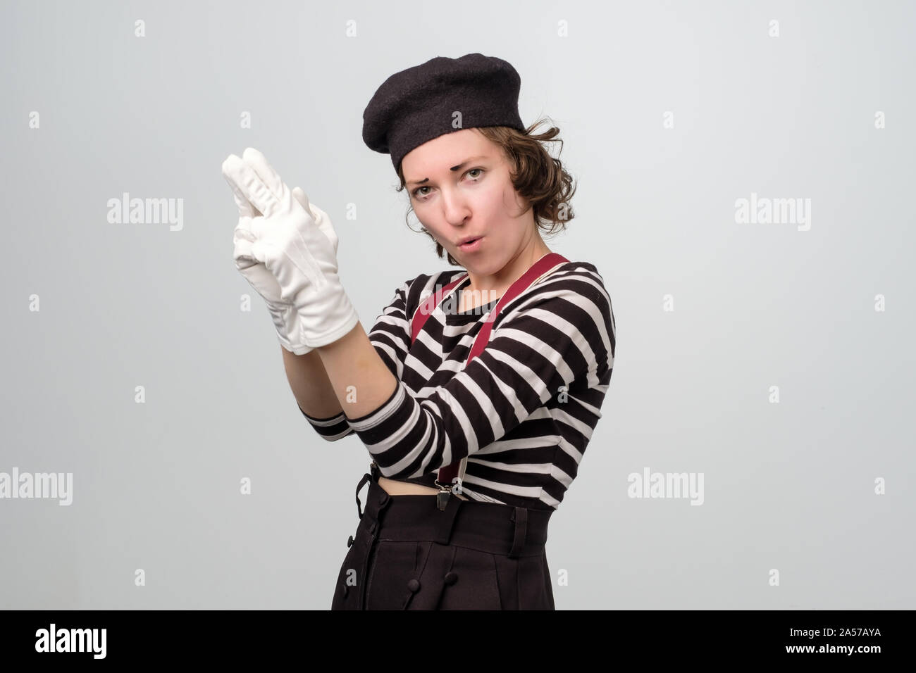 Mime-Frau zeigt mit Fingern wie Pistole, an der Kamera schauen und lächeln. Stockfoto