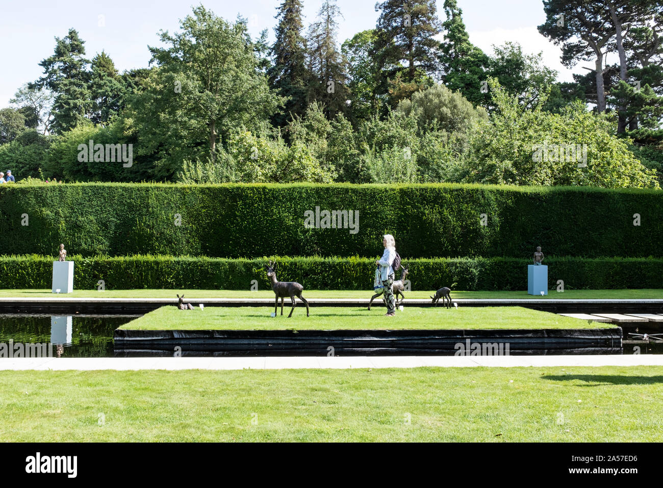 Eine Frau entspannt unter den Hirsch Skulpturen und Pool von Kiftsgate Court Gardens Stockfoto