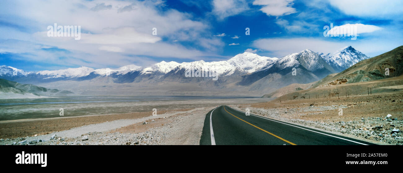 Landstraße, die durch eine karge Landschaft, Muztagh Ata, Karakorum Highway, Provinz Xinjiang, China Stockfoto