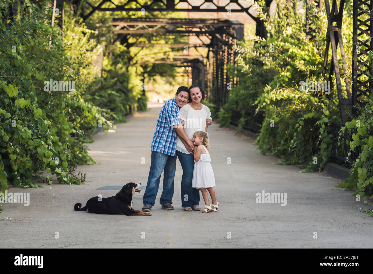 Bezaubernd lächelnde Blonde 4-jährige Mädchen in sundress in der Nähe von üppiger Pflanzen Stockfoto