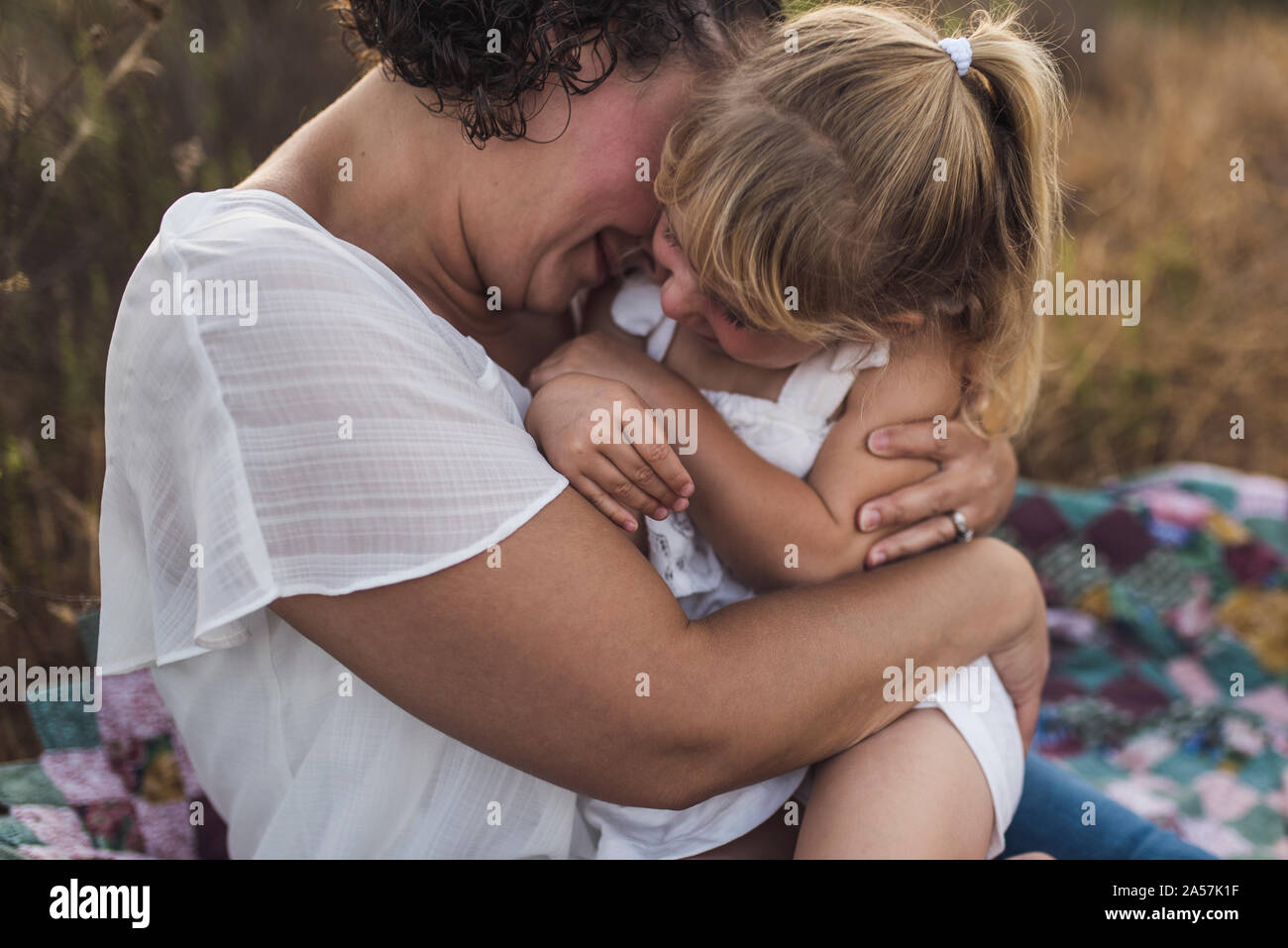 Mama kuscheln 4 Jahre altes Mädchen im Freien auf quilt Stockfoto
