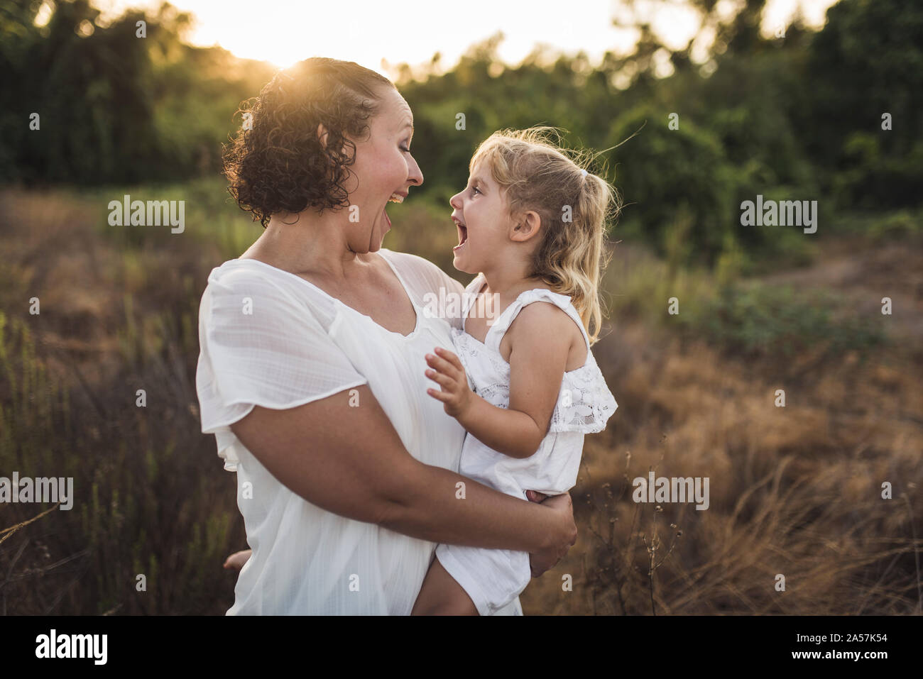 Riesige lächelt während Mama hält 4 Jahre alten in eine sonnige Wiese Stockfoto