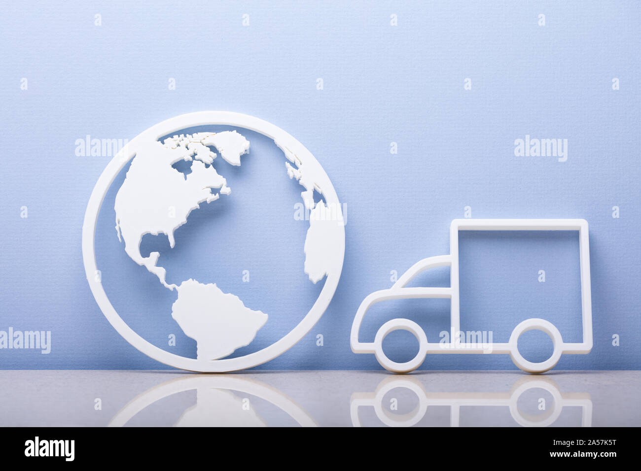 Nahaufnahme einer Welt Symbol- und Lkw-Symbol lehnte sich auf blauen Wand Stockfoto