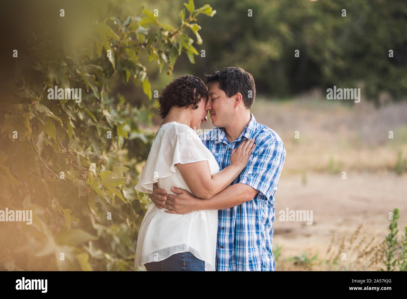 Mann und Frau umarmen im Freien in der Nähe von Tree-B/W-Foto Stockfoto