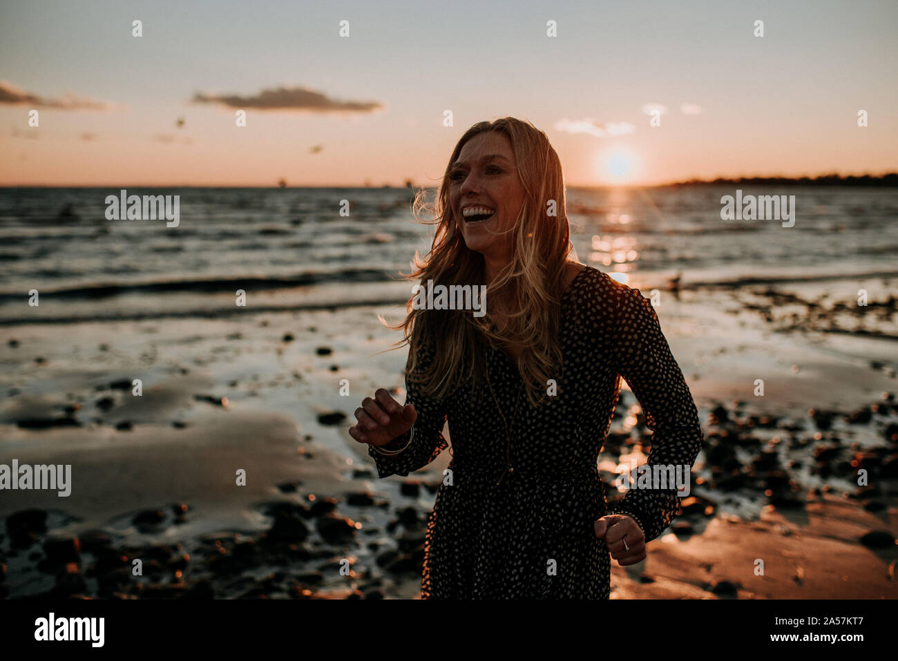 Frau am Strand bei Sonnenuntergang lachen Stockfoto