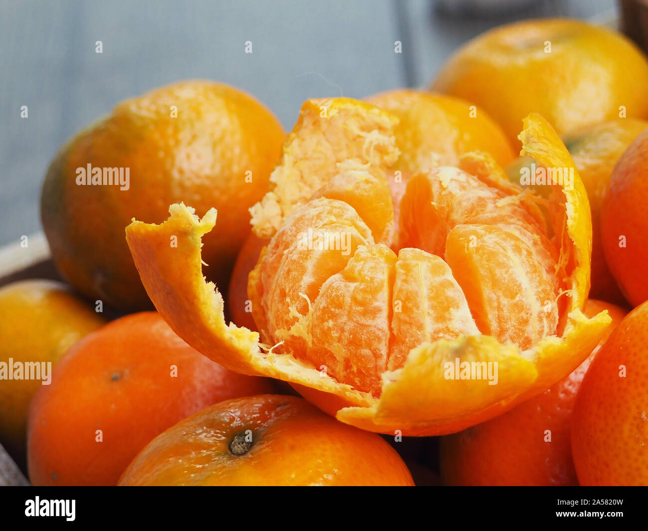 Holzkiste mit Mandarinen gefüllt. Eine Tangerine ist geschält. Neues Jahr Konzept. Stockfoto