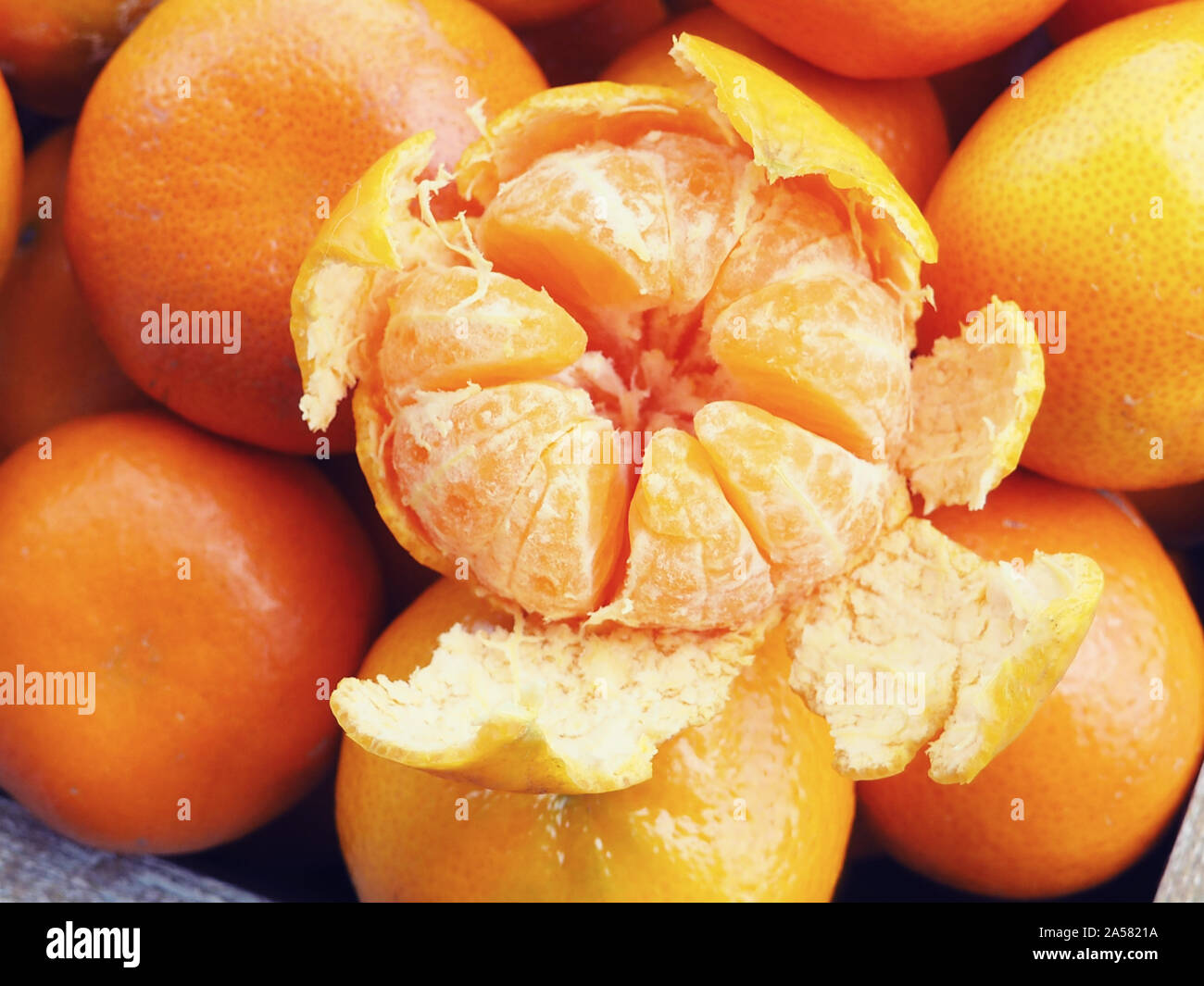 Holzkiste mit Mandarinen gefüllt. Eine Tangerine ist geschält. Neues Jahr Konzept. Stockfoto