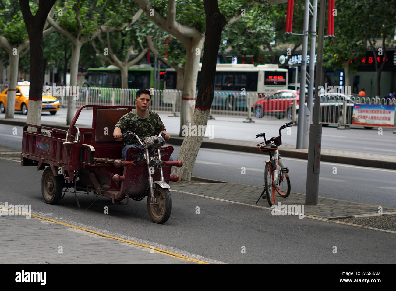 Mann, ein Dreirad, Moped mit Laderaum über die Straße Stockfoto