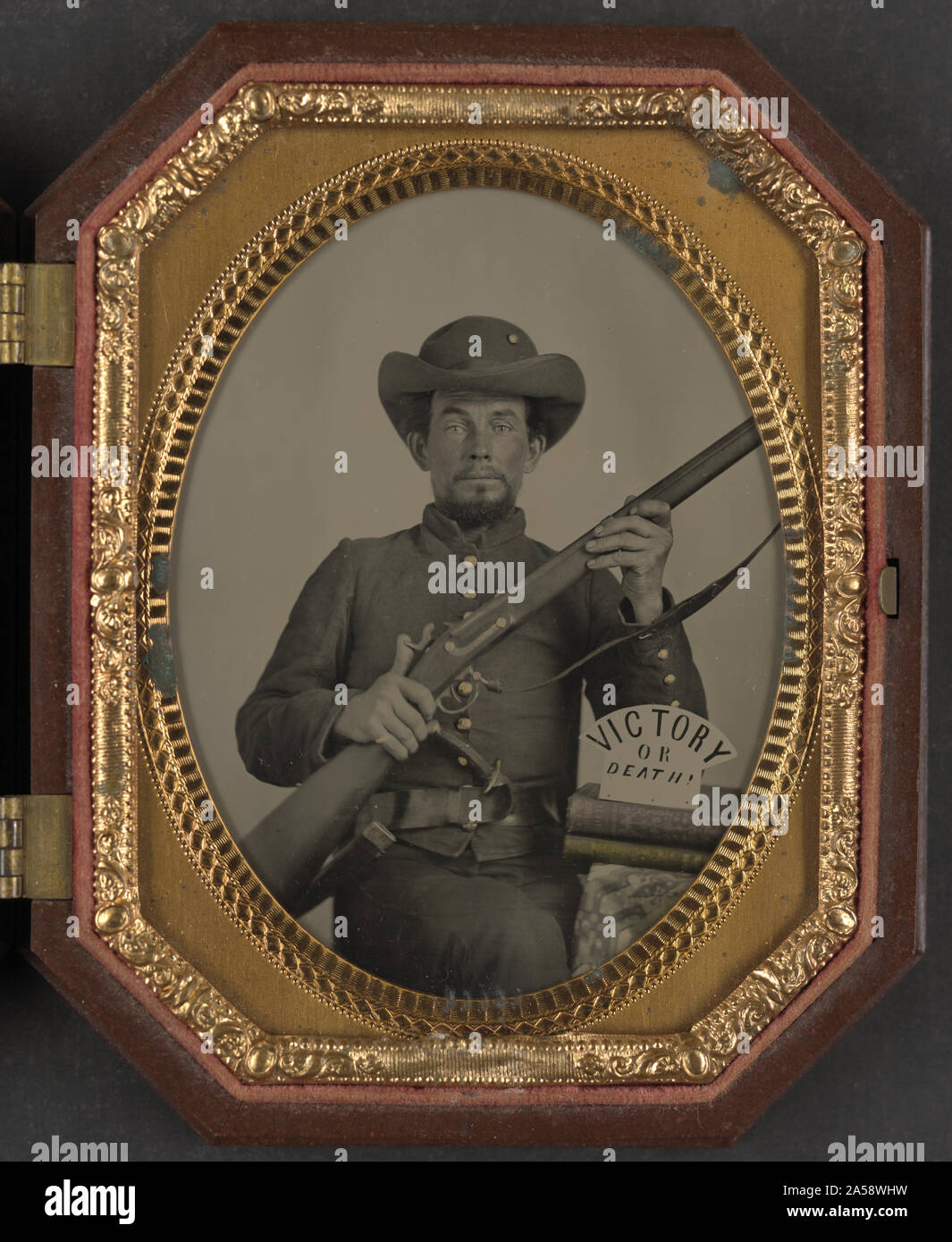 Unbekannter Soldat in Confederate Uniform mit Muskete, Messer, und Zeichen lesen Sieg oder Tod! Auf zwei Bücher Stockfoto