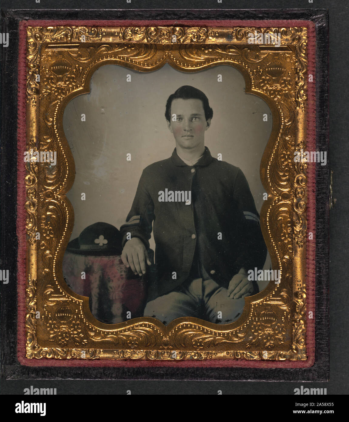 Unbekannter Soldat in der Union Corporal einheitliche Arm ruht auf Tisch mit 2 Korps, Armee des Potomac slouch Mütze auf der Oberseite Stockfoto