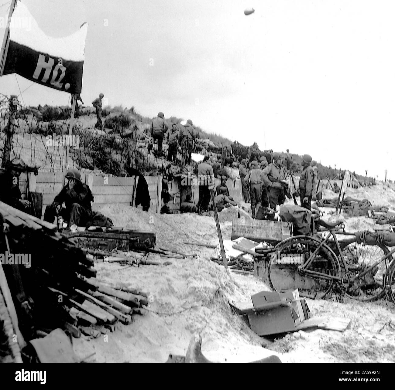 [ORIGINAL CAPTION] Männer und Ausrüstung verstreut über einen Befehl post am Roten Strand, Frankreich. Einige G.I. würden nicht Teil mit seinen englischen Racer, damit er es über (Hinweis rechts) gebracht. 8. Juni 1944. Red Beach, Frankreich. Stockfoto