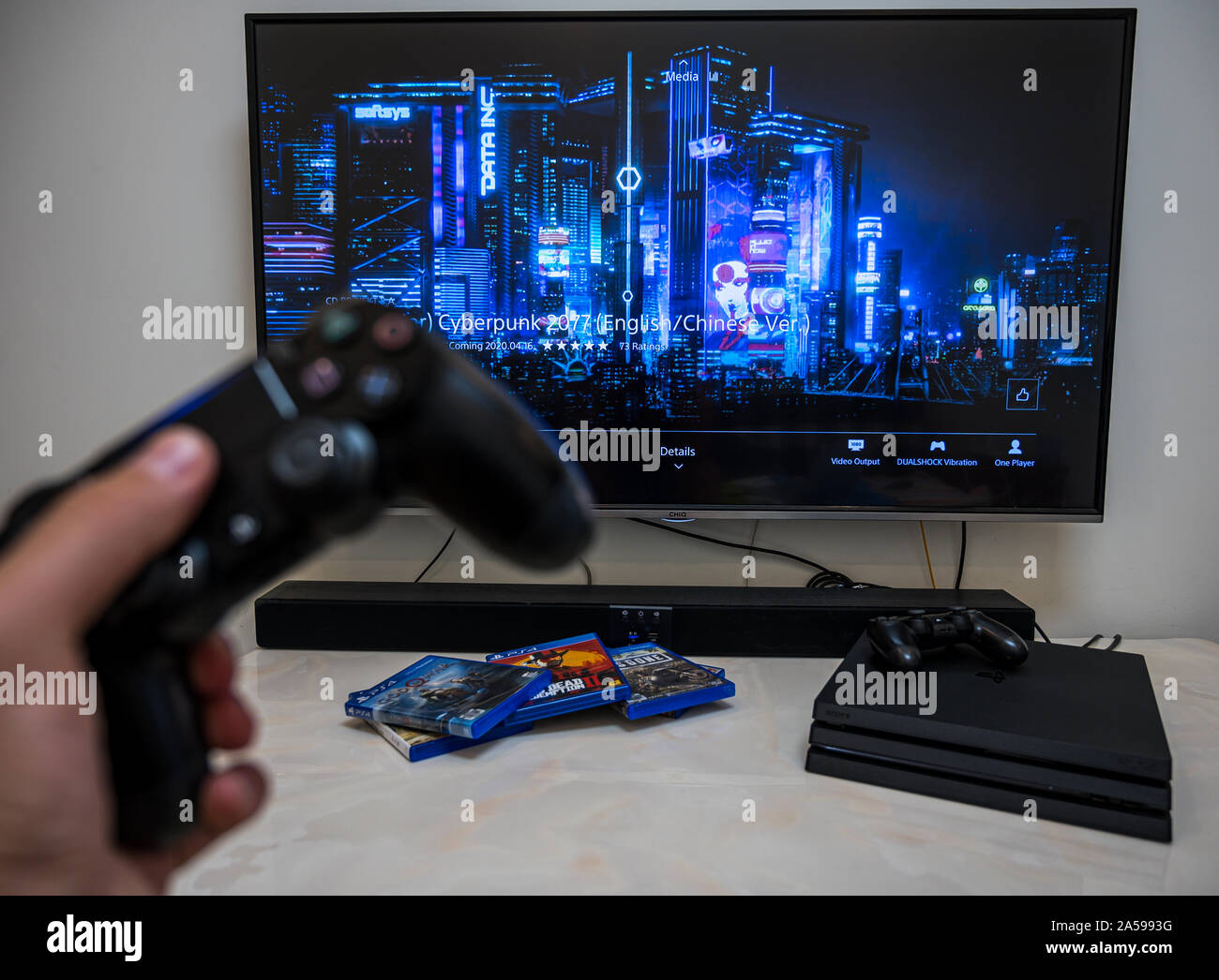 Pre-order, herunterladen, abspielen Sony Play Station 4 Pro Spiel Cyberpunk 2077 auf dem großen LCD-Bildschirm zu Hause. Controller in der Hand. Stockfoto