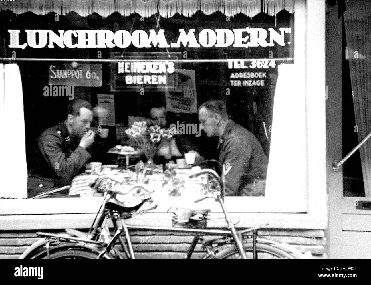 Deutsche Soldaten an einem modernen Speisesaal in der Long Street (langestraat) 1941 in Essen Stockfoto