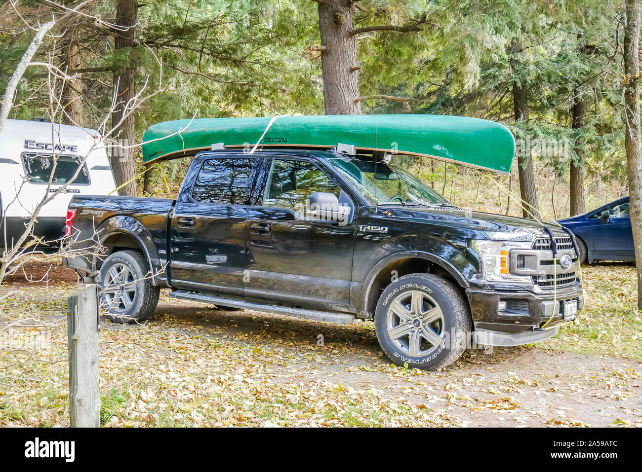 Ein schwarzer Ford F150 Trunk mit einem grünen Kanu auf dem Dach montiert Stockfoto