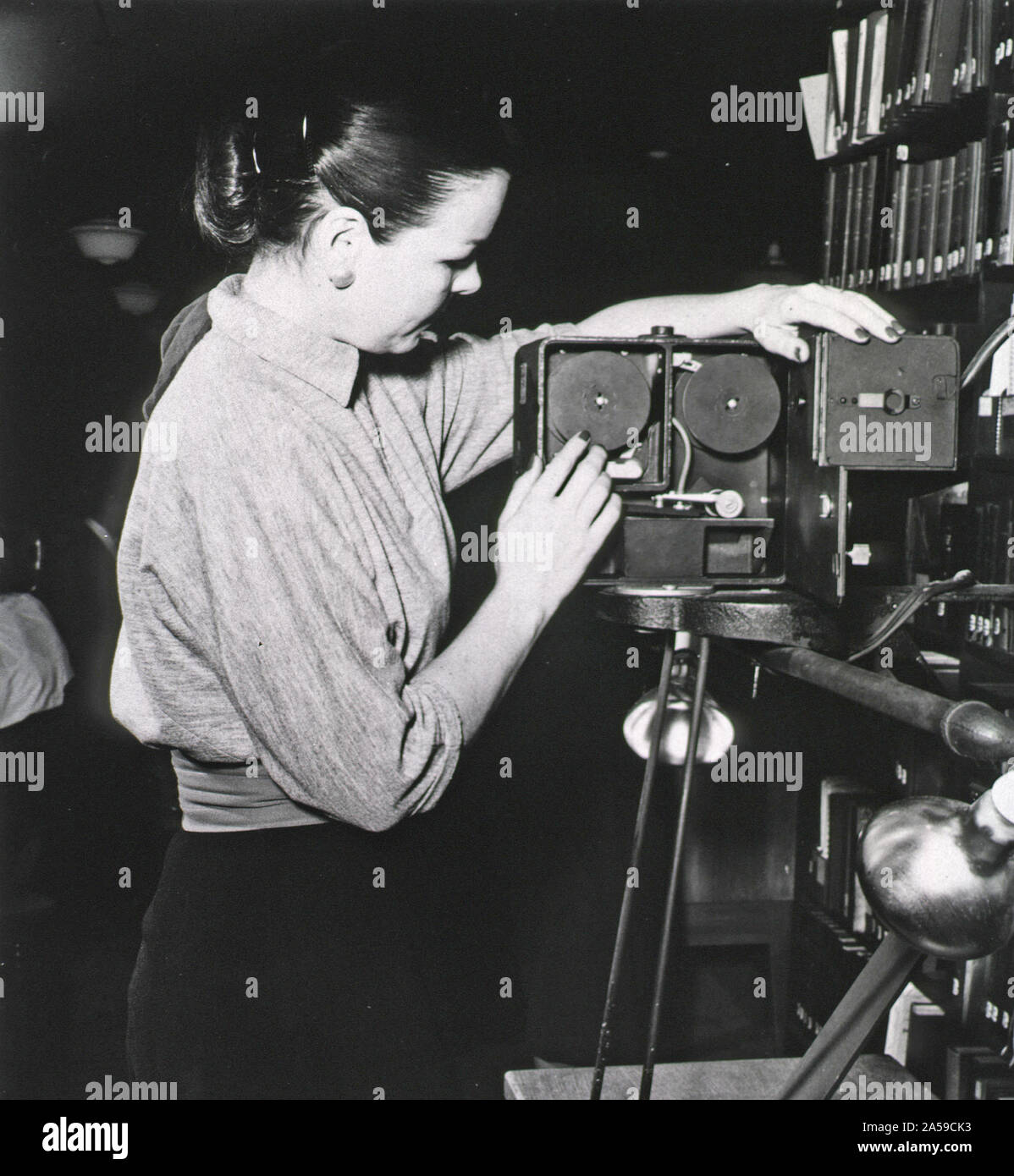 Eine Frau steht mit einem Kodak Recordak Fall öffnen, ist aufschlussreich Filmrollen. Stockfoto