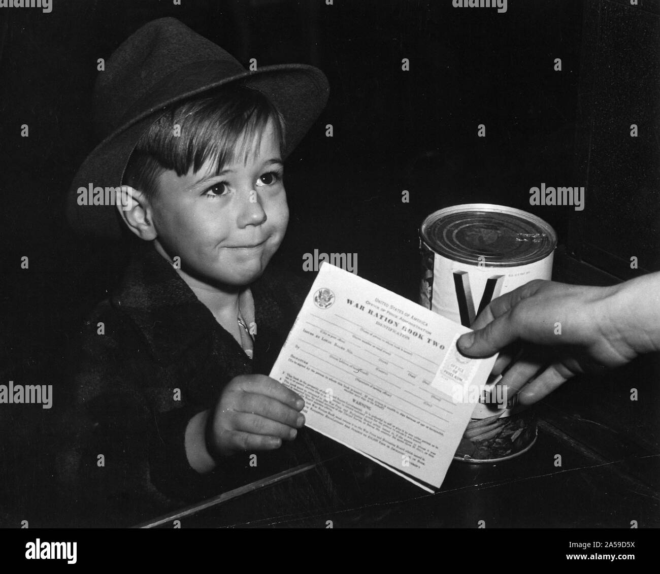 Ein eifriger School Junge bekommt seine ersten Erfahrungen mit Krieg Bezugsschein Zwei. Mit vielen Eltern im Krieg beschäftigt sind, Kinder gelehrt, die Fakten der Punkt Rationierung für die Hilfe in der Familie marketing., Ca. 02/1943 Stockfoto