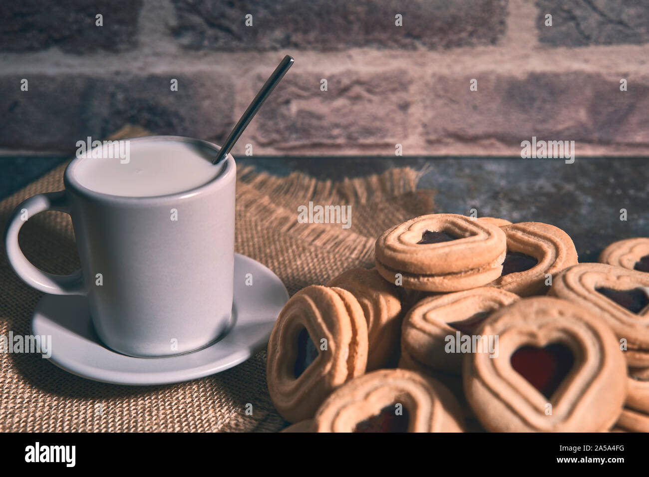 Tasse Milch auf einem Lappen neben ein paar leckere Cookies. Essen Konzept Stockfoto