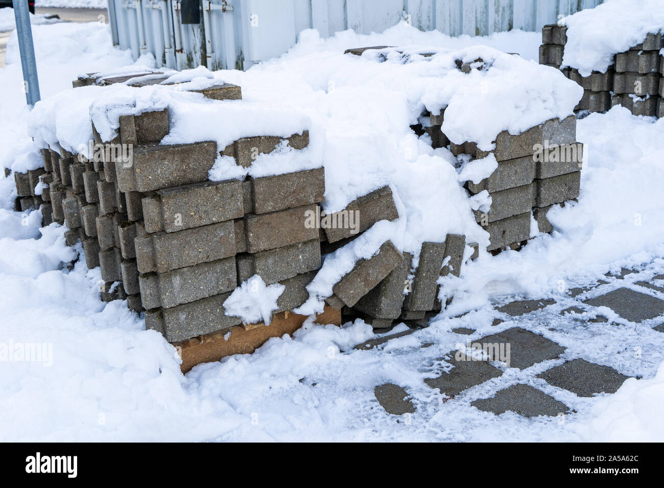 Pflastersteine auf einem Haufen sind mit Schnee bedeckt, während einige der Steine nach unten bereits gefallen sind. Stockfoto