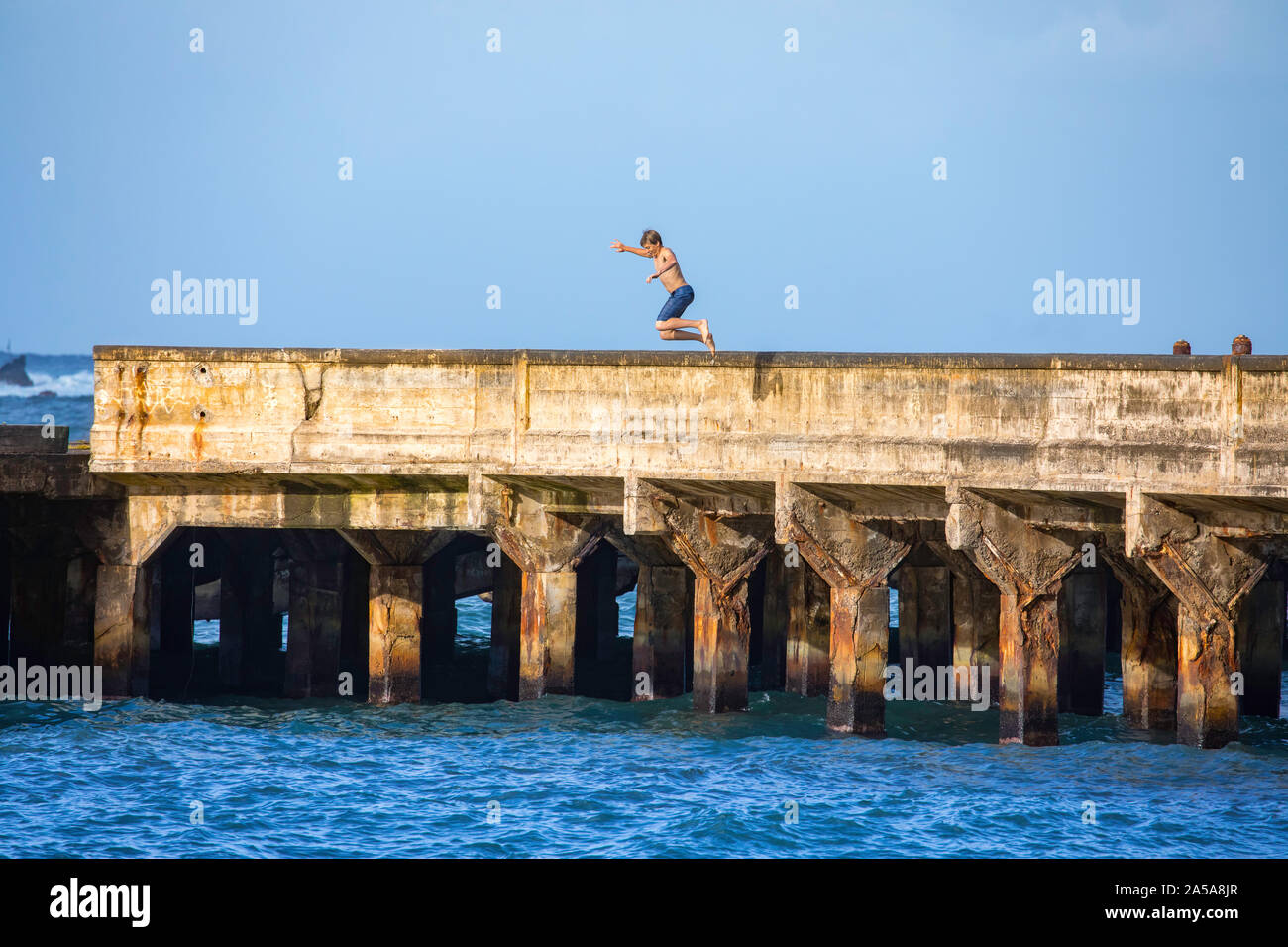 Ein junger Mann, MR, springt von der Werft in Hana Bay, Maui, Hawaii. Stockfoto