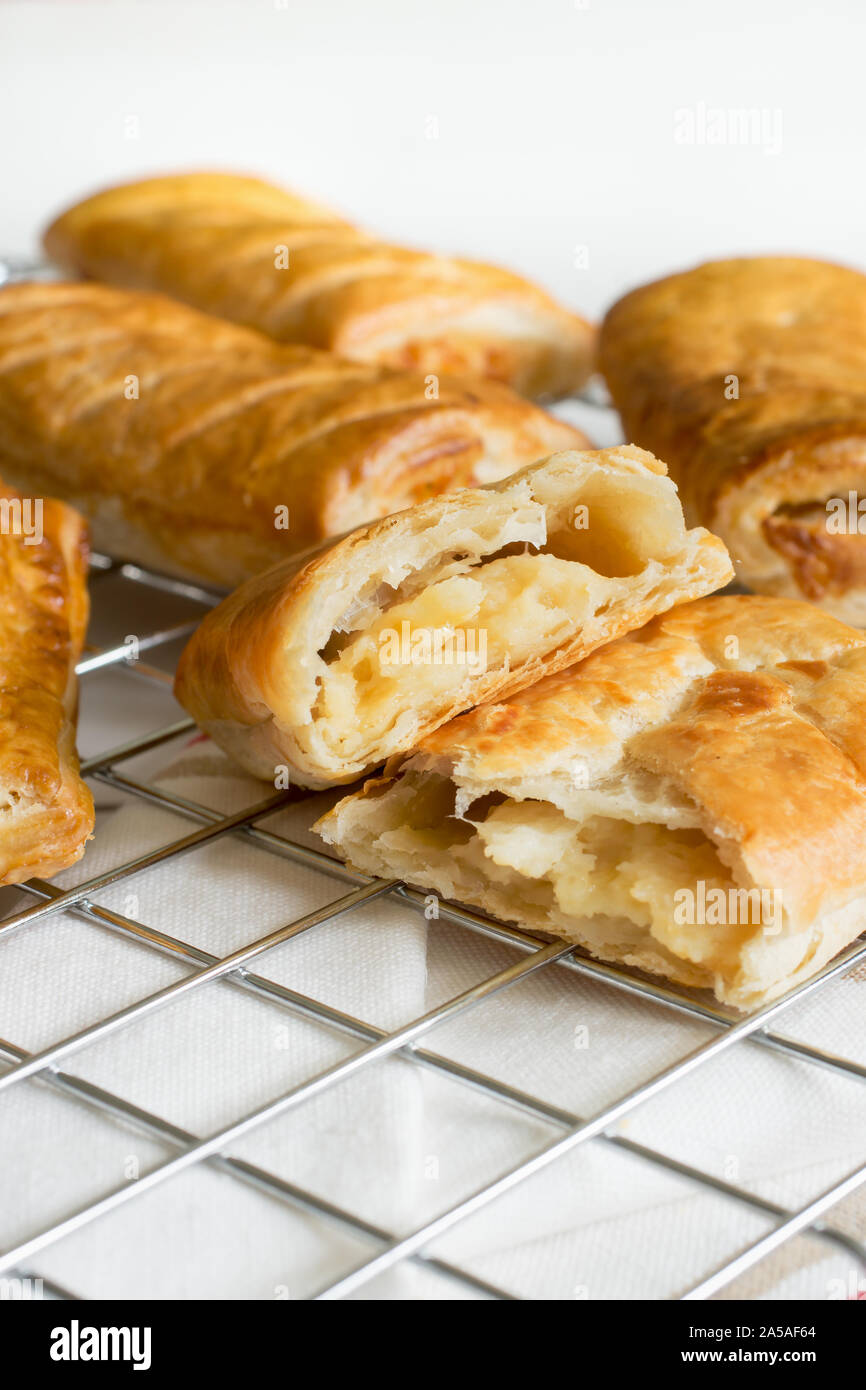 Herzhafte Käse und Zwiebeln Blätterteig Brötchen frisch aus dem Ofen Kühlung auf einem kochen Untersetzer eine vegetarische Alternative zu den üblichen Wurstbrötchen Stockfoto