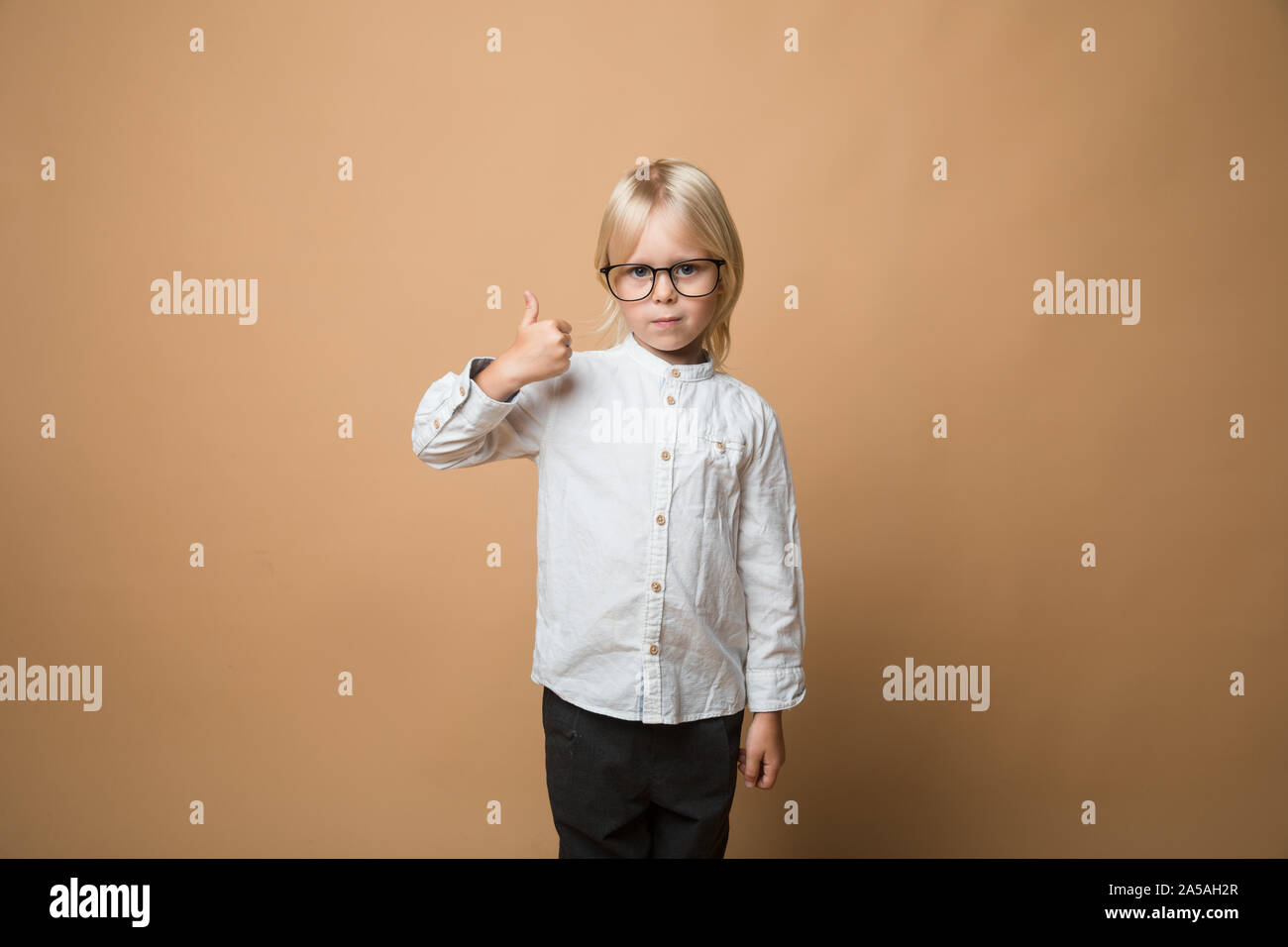 Der kleine Junge hat eine großartige Idee, gibt er zwei Daumen hoch und ist sehr glücklich. Schule Stockfoto