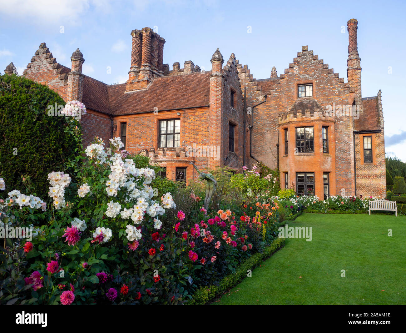 Chenies Herrenhaus nach Westen. schönem Wetter, blauer Himmel und alten Mauerwerk in der Sonne mit Colouful Dahlien, Kosmos und Rosen in voller Blüte. Stockfoto