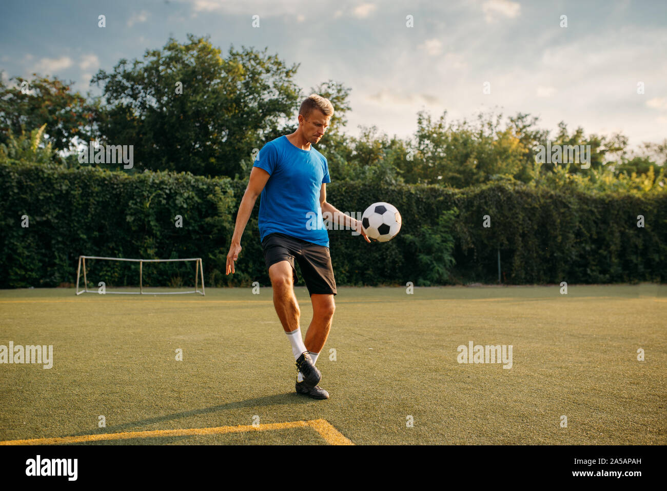 Männliche Fußballspieler stopft den Ball mit dem Fuß Stockfoto