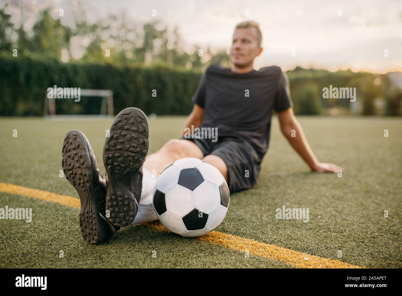Männliche Fußballspieler mit Ball auf dem Rasen sitzen Stockfoto