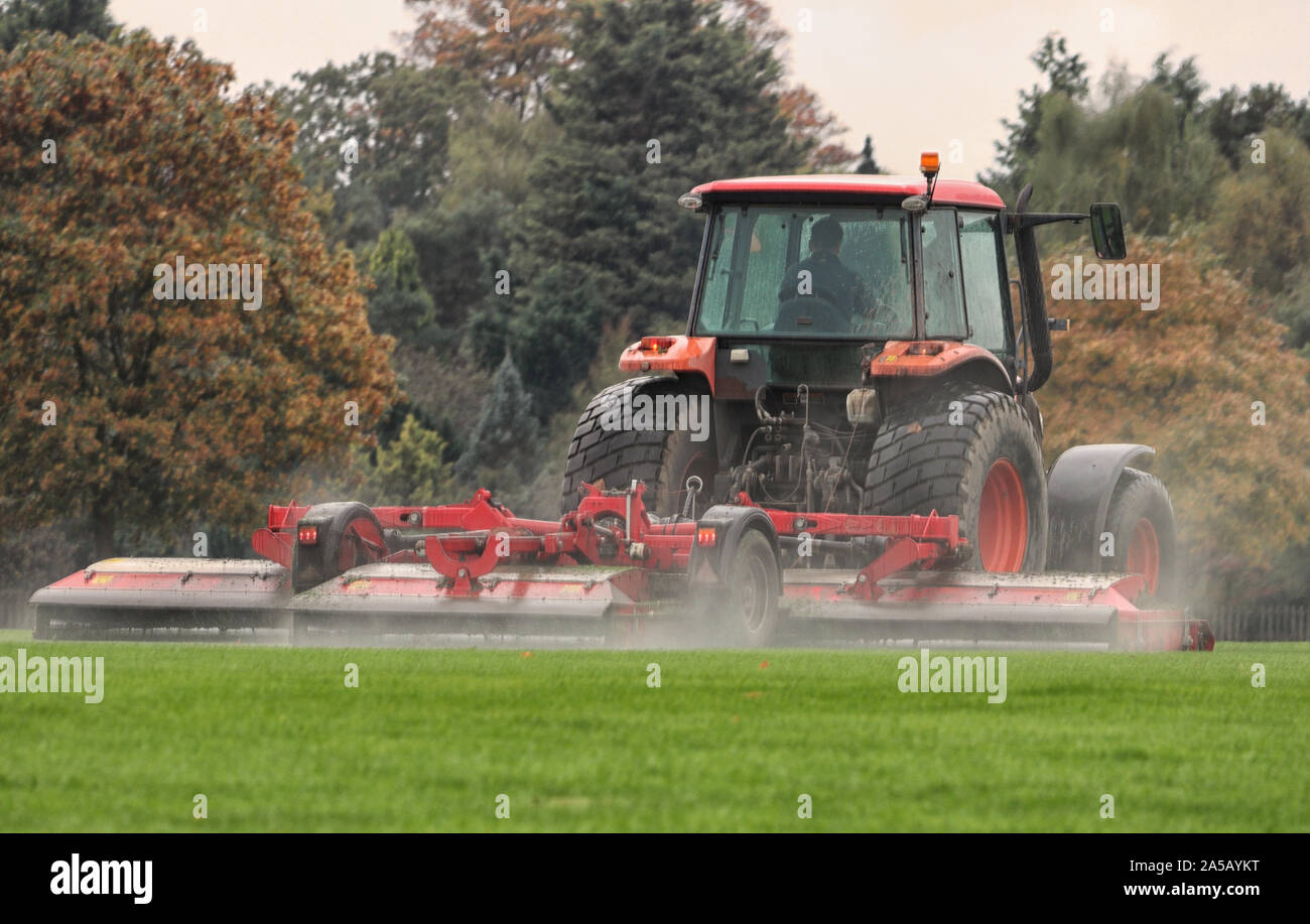 Traktor mit Anhänger Mähen von Gras mit Wasser spritzen in der Luft Stockfoto