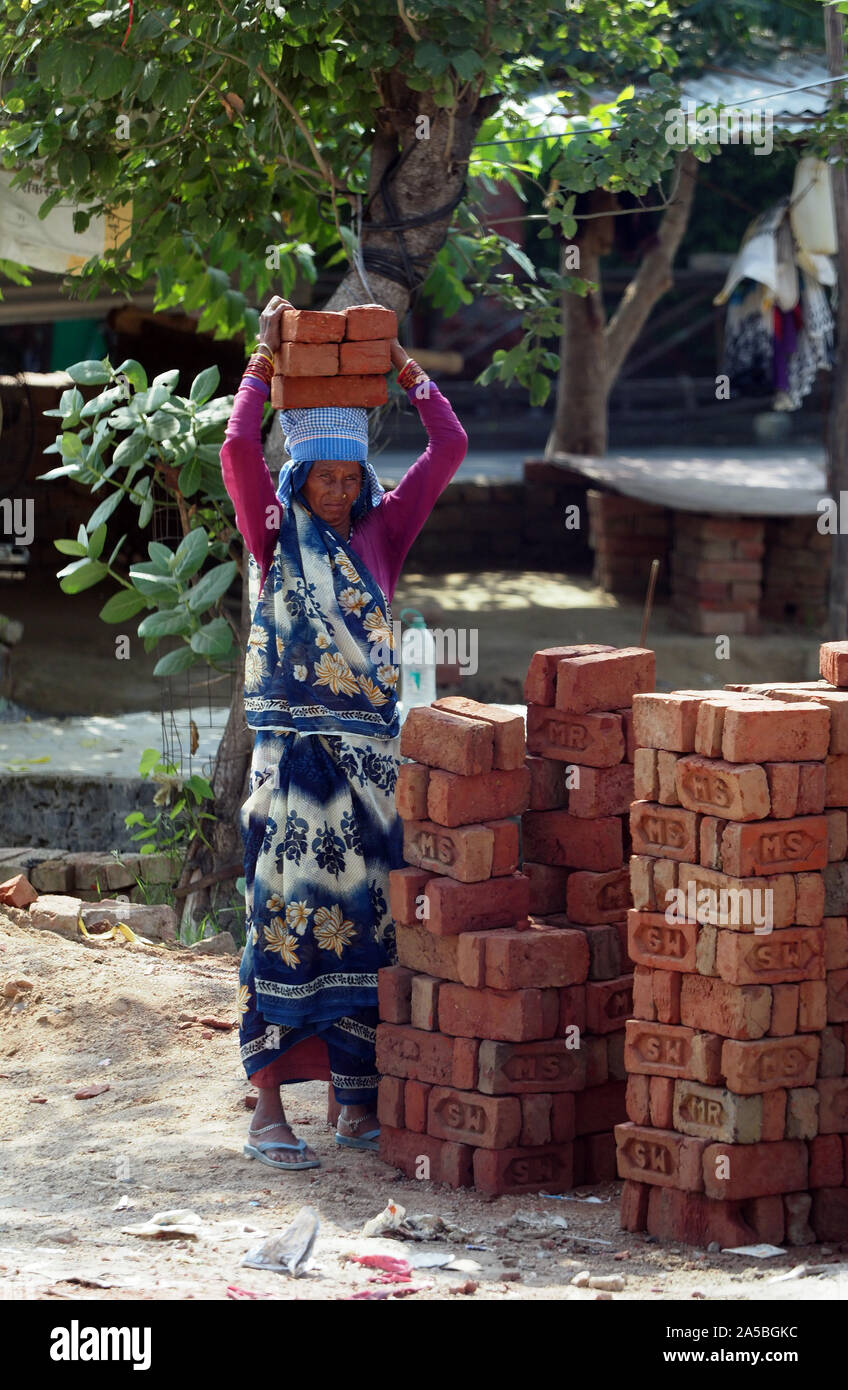 Eine Frau, die Ein- und Durchführung von Backsteinen auf ihren Kopf auf einer Baustelle in Agra, Indien. Stockfoto