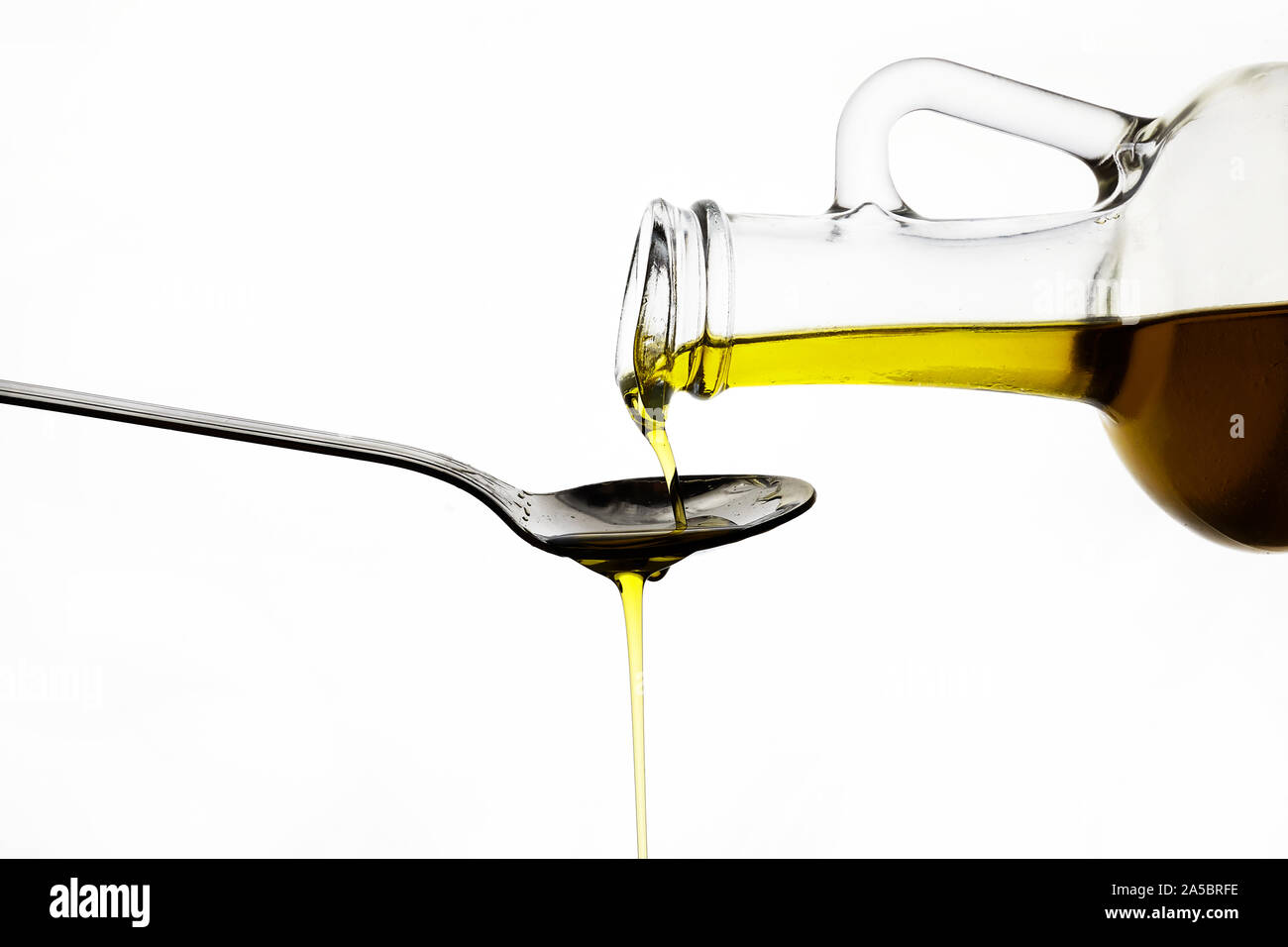 Gießen Olivenöl aus Glas Flasche auf weißem Hintergrund Stockfoto