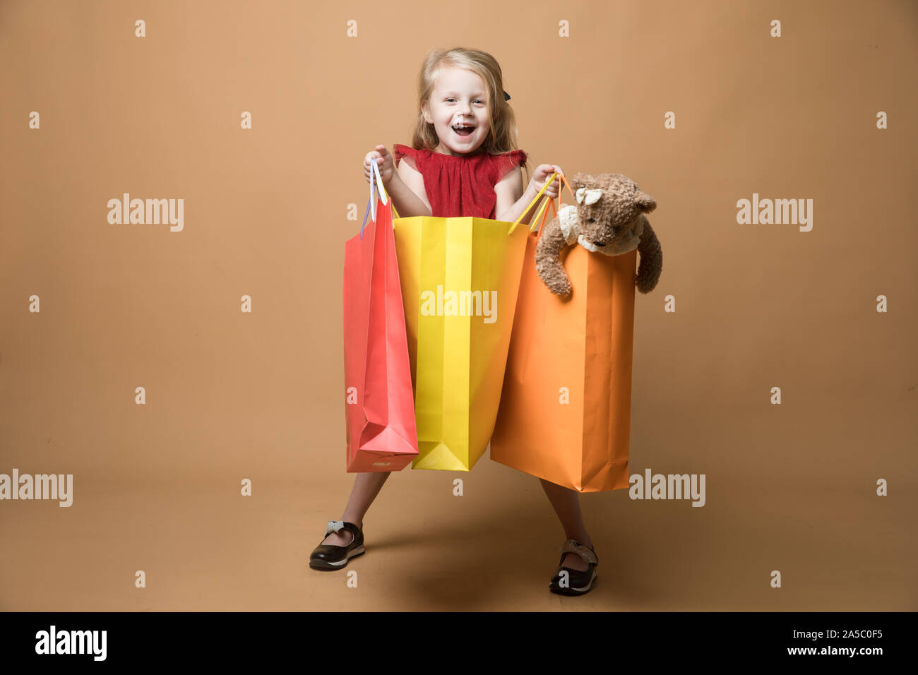 Ein junges Mädchen im roten Kleid und mit Einkaufstüten, Happy Shopping Stockfoto