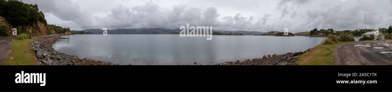 Blick von der Portobello Road von der Halbinsel Otago, Dunedin mit einem Boot und einem felsigen Strand über die Lagune. Stockfoto