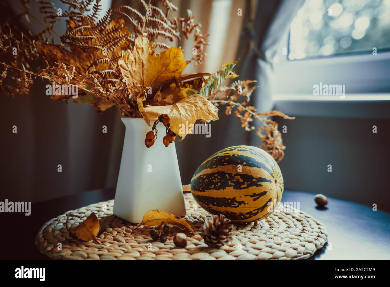 Schnen Herbst noch Leben mit Blumenstrau der fallenden Bltter, Farn,  Hagebutte in der Vase und dekorative gestreiften Krbis auf dem Stroh  Serviette. Natrliche Dekoration Stockfotografie - Alamy