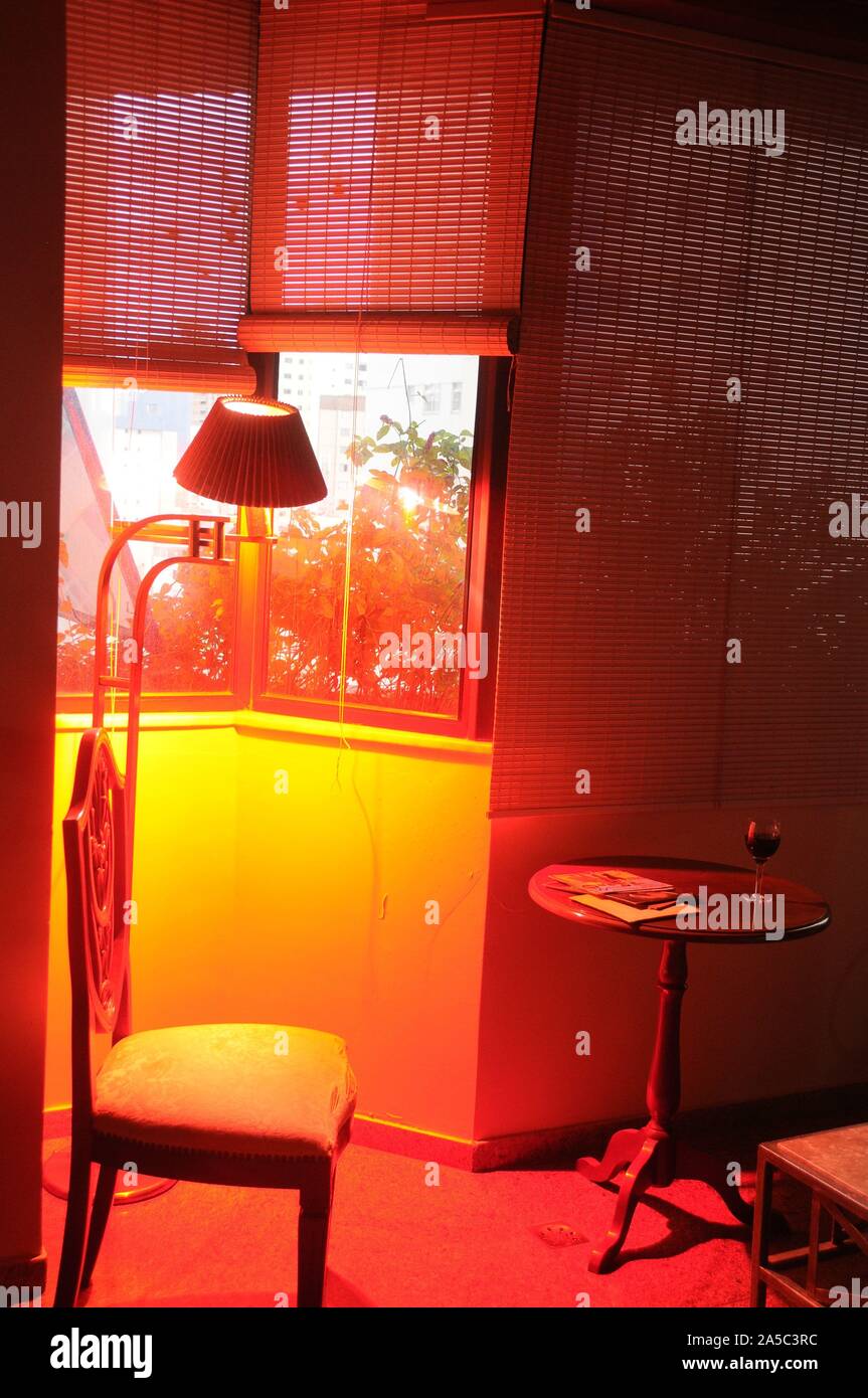 Stuhl unter FENSTER MIT ROTEM LICHT AUS HINTERGRUND. Stockfoto