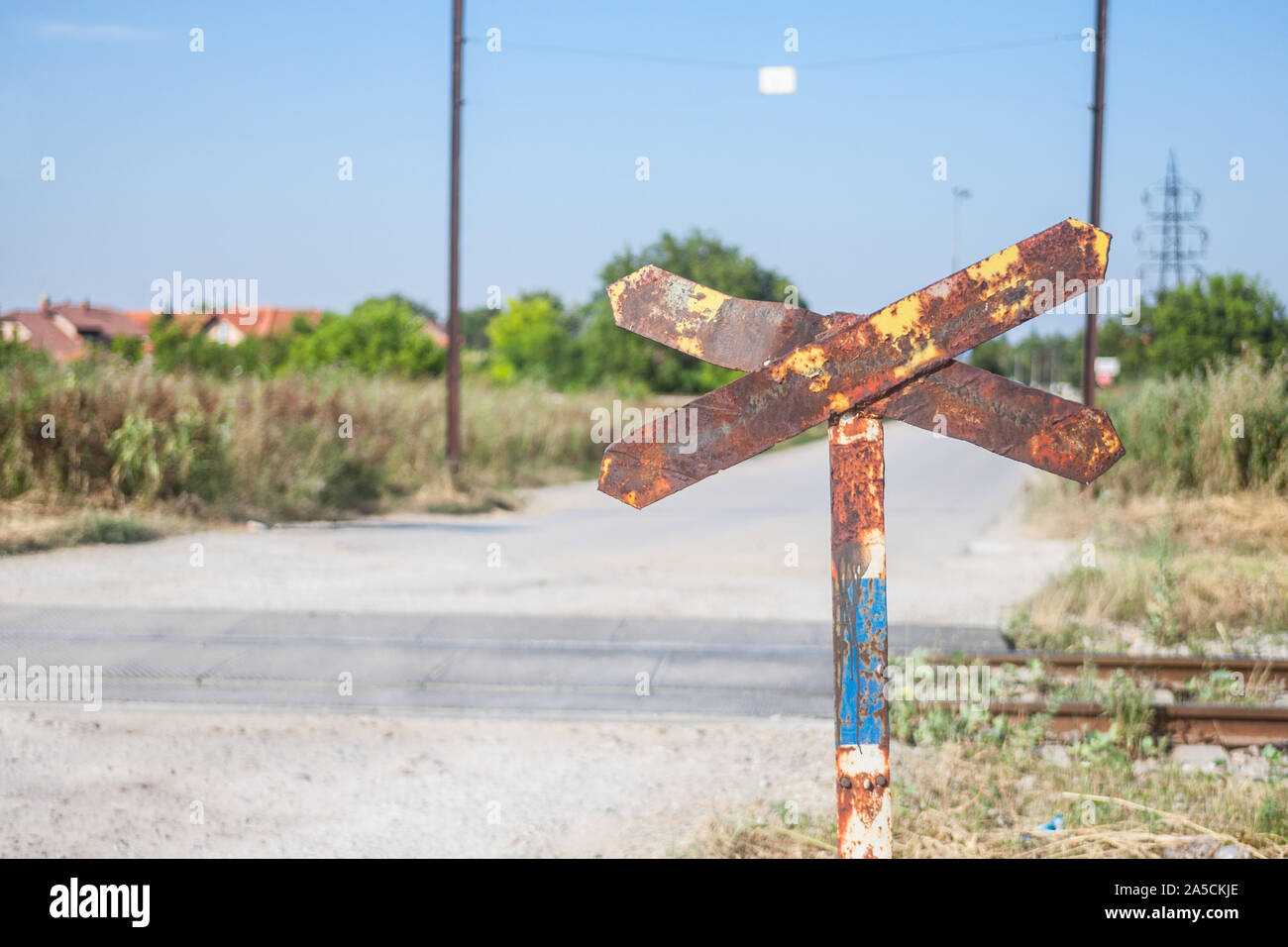 Bahnübergang Zeichen, genannt crossbuck, saltire oder Saint Andrews Kreuz, verrostet, stehend auf einer Landstraße, die Kreuze und verlassenen Bahnhof trac Stockfoto