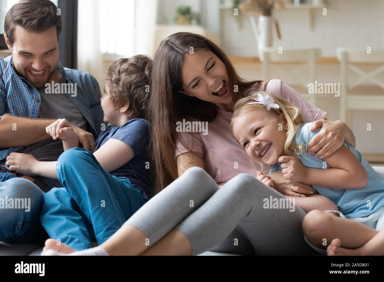 Glückliche Familie Spaß haben, lachen Eltern kitzeln Tochter und Sohn Stockfoto