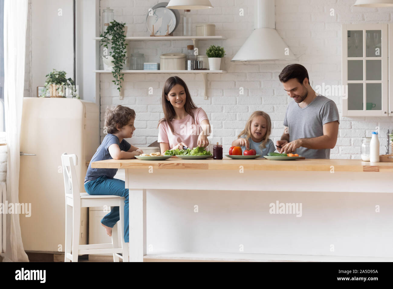 Glückliche Familie mit kleinen Kindern vorbereiten Salat zusammen Stockfoto