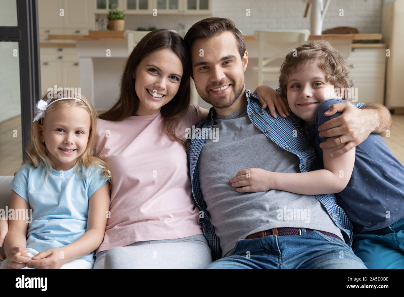 Portrait glückliche Familie, Eltern mit kleinen Kindern zu Hause umarmen Stockfoto