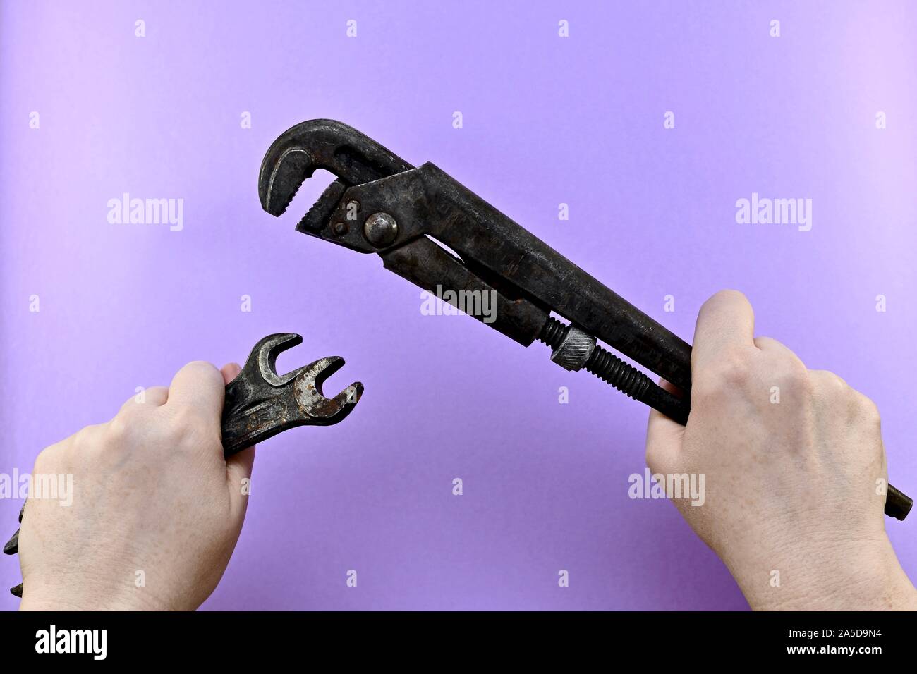Bügeleisen Werkzeugen, Schlüsseln und verstellbarer Schraubenschlüssel, in starken weiblichen Händen. Stockfoto