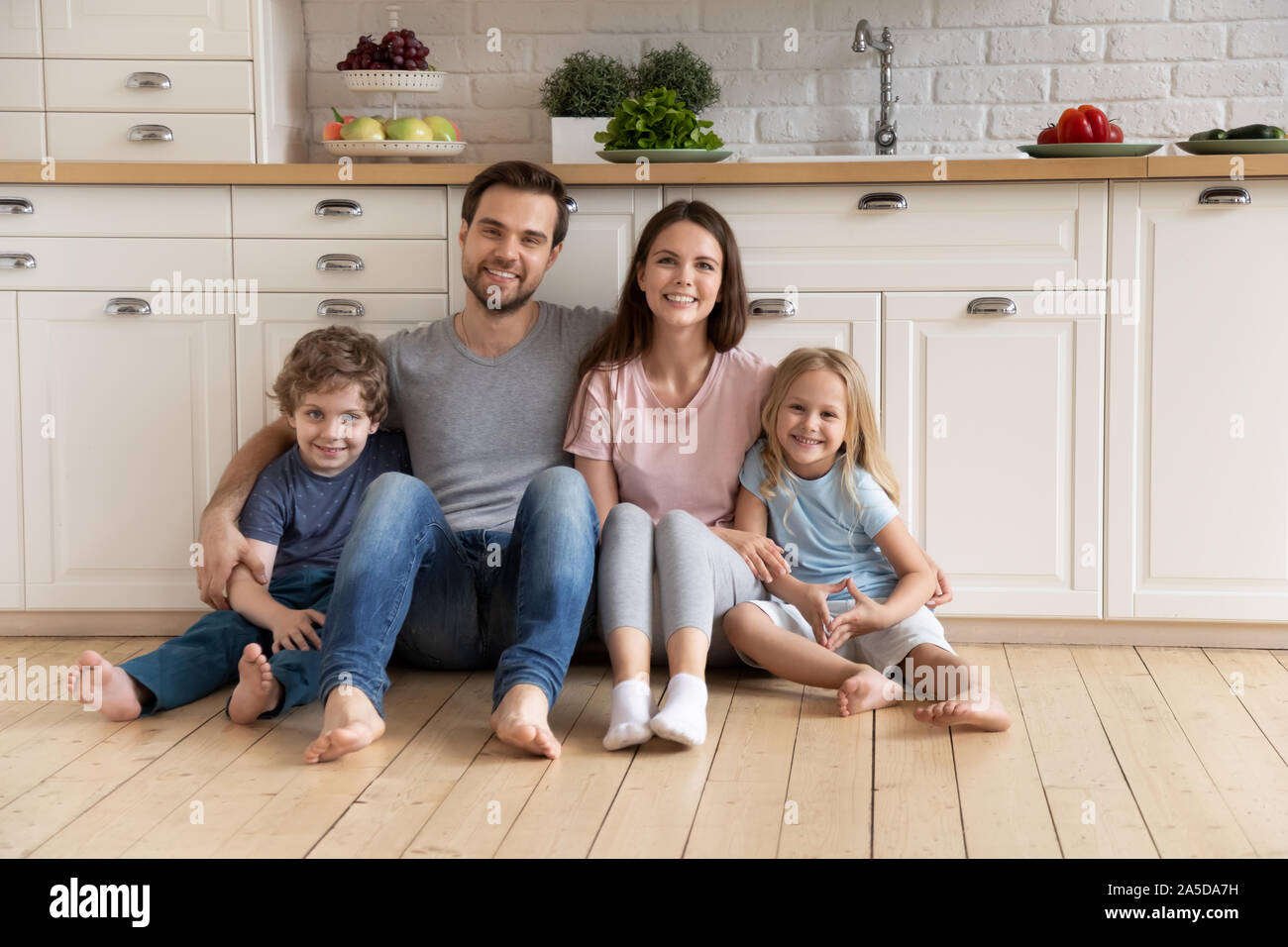 Portrait happy family umarmen, sitzen auf den warmen Boden in der Küche Stockfoto