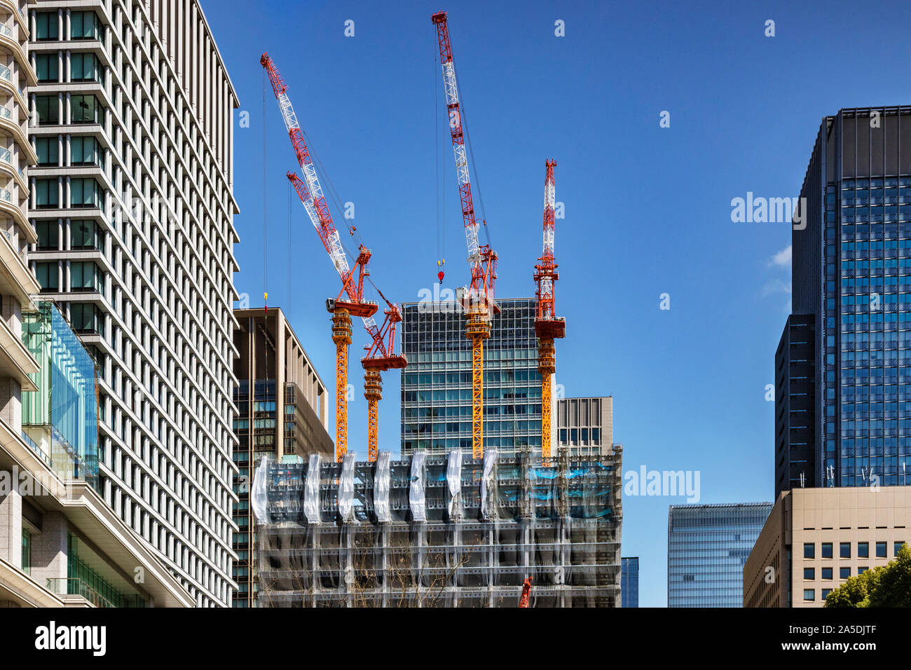 21. März 2019: Tokyo, Japan - Krane arbeiten auf ein neues Bürogebäude im Zentrum der Stadt, in der klare, blaue Himmel. Stockfoto