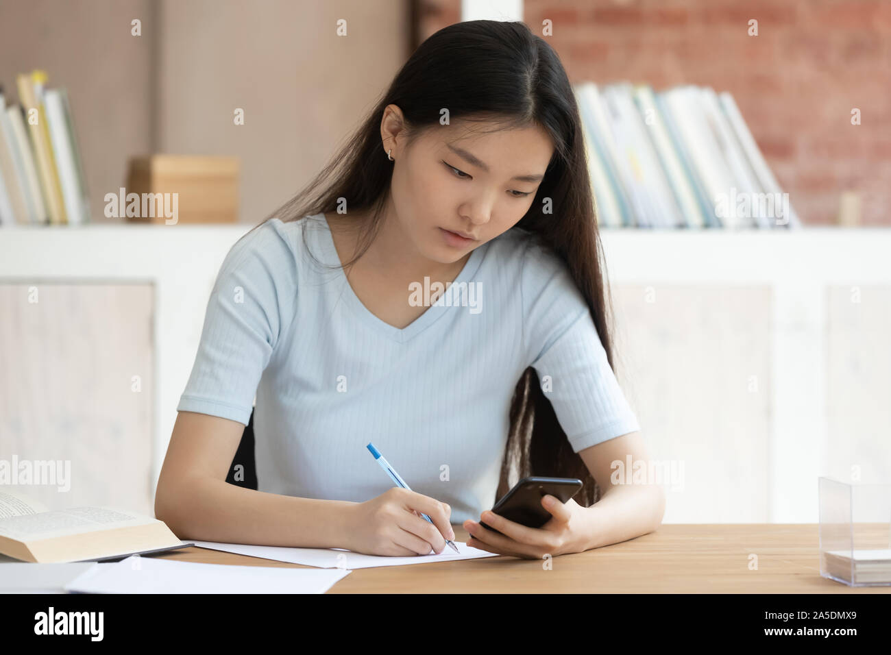 Asiatische Ethnie Schülerin mache Hausaufgaben in der Bibliothek Schreibtisch sitzen Stockfoto