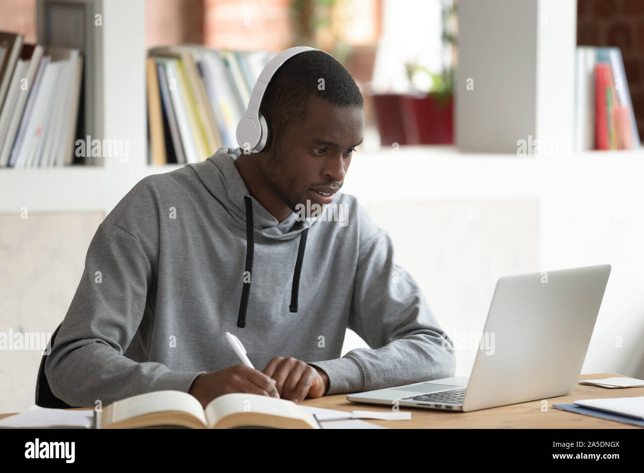 Afrikanische Kerl e-Learning in der öffentlichen Bibliothek am Schreibtisch sitzen Stockfoto