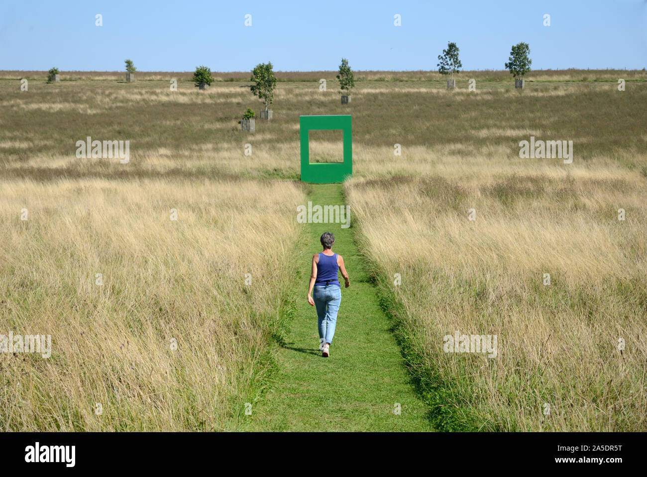 Europäische Frau Entlang gemähten Grases im Feld mit grünen Wohnung Kunst Installation von Krijn de Koning 2019 im Hintergrund Compton Verney England Stockfoto