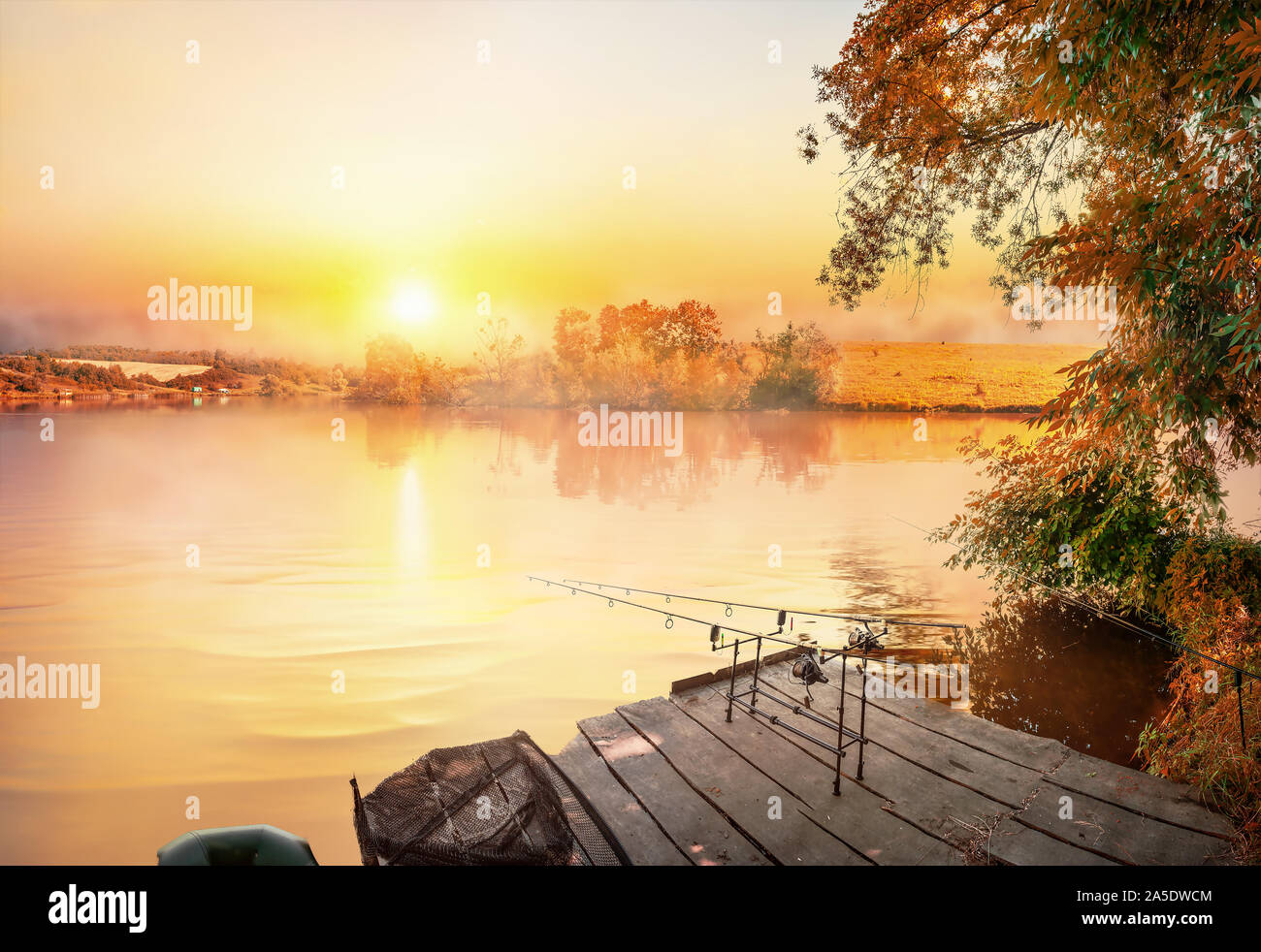 Angelausrüstung auf hölzernen Pier und ruhigen Fluss am Morgen Stockfoto