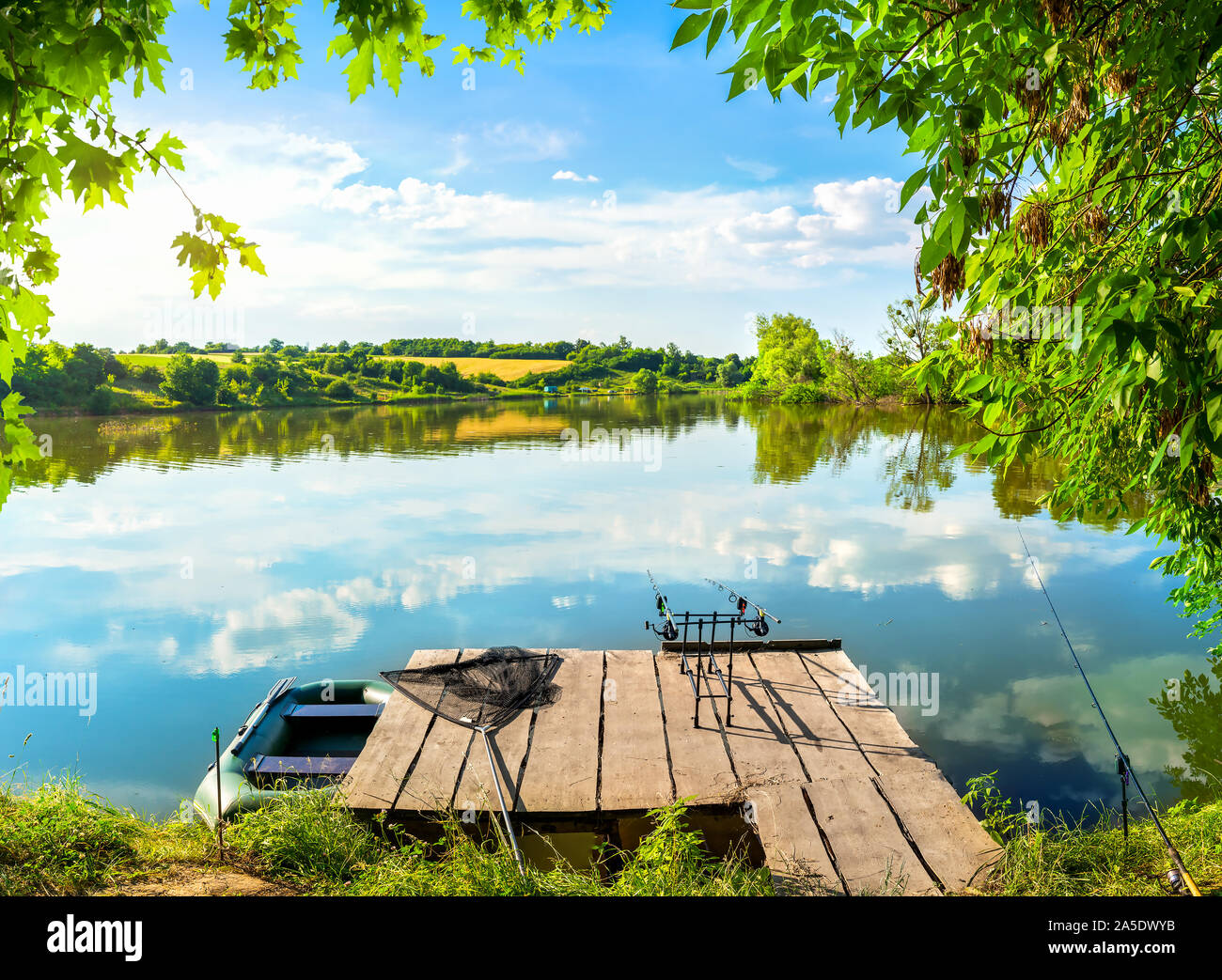Angelausrüstung auf hölzernen Pier und ruhigen Fluss am Morgen Stockfoto