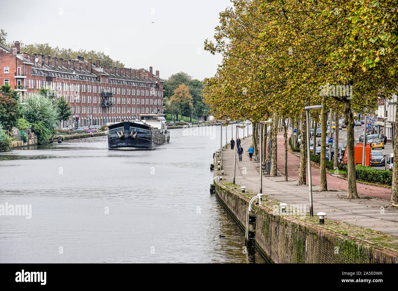 Rotterdam, Niederlande, 14. Oktober 2019: binnenschiff Bewegen durch die geschwungene Delfshavense Schie Kanal mit Platanen gesäumt und frühen 20 c Stockfoto